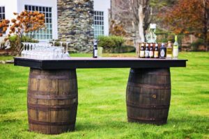 Table made out of two barrels placed on grass with drinks sitting on top